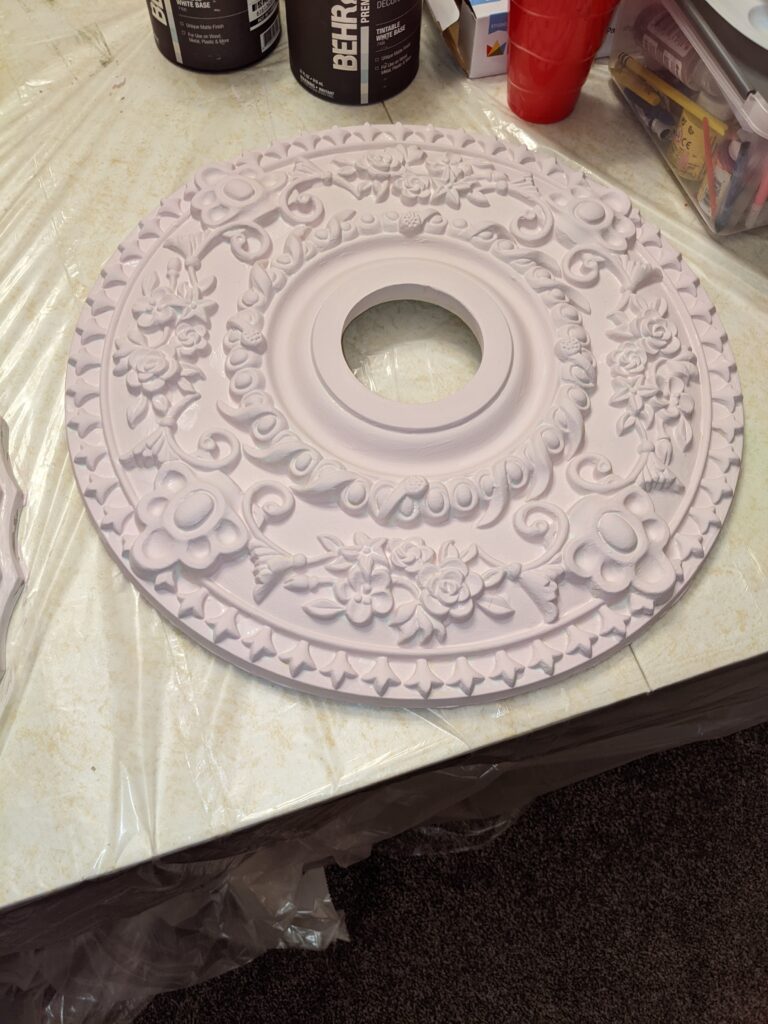 Ceiling medallion after, painted light pink with brushes of grey and gold.